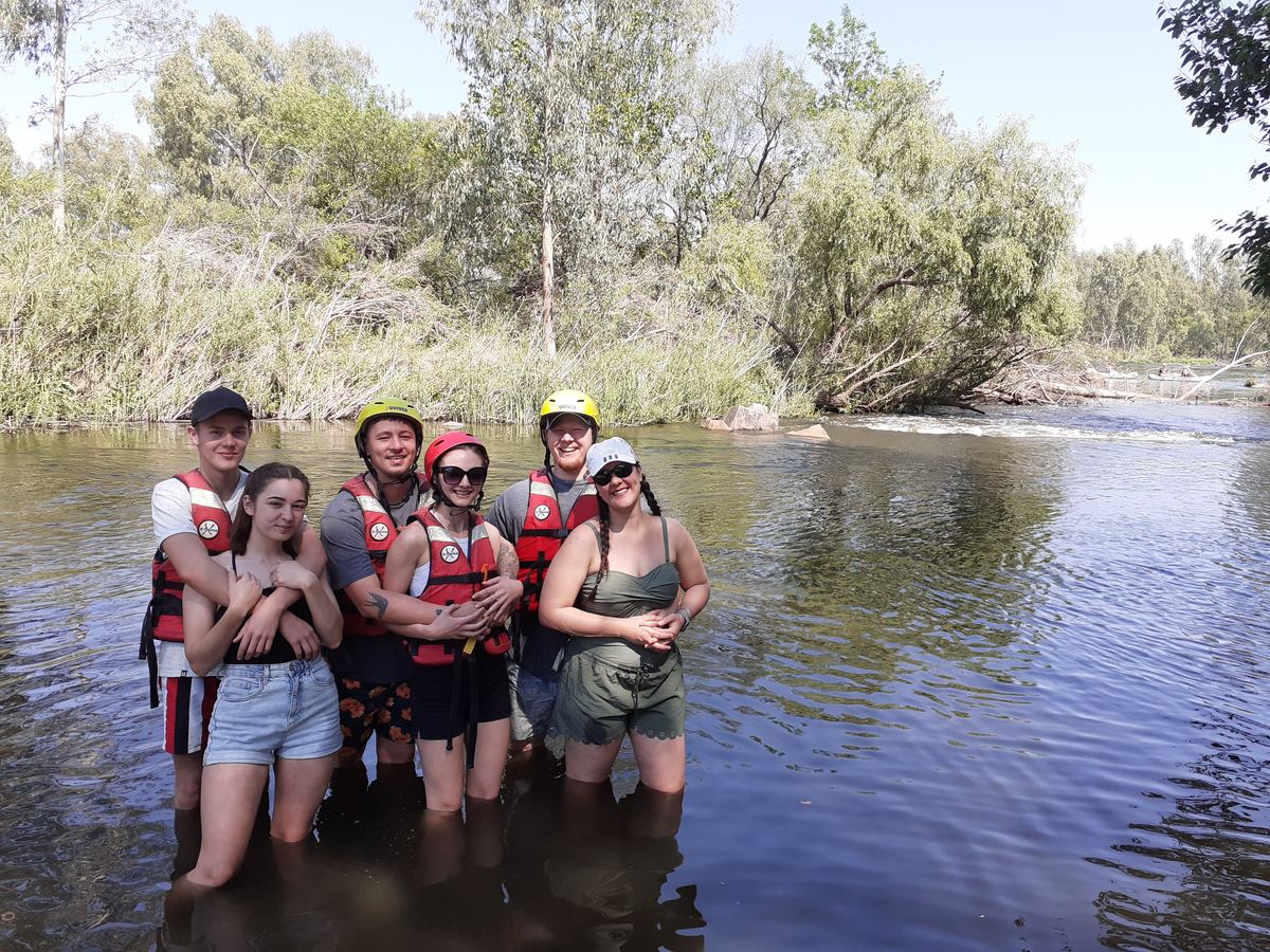 Young people in life jackets standing in the river